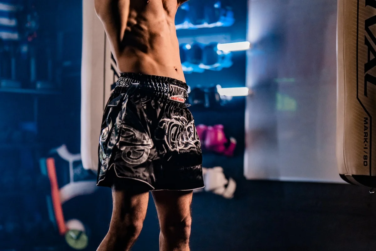 Athlete performing a kettlebell swing at peak of the movement inside a boxing gym, mid-HIIT session
