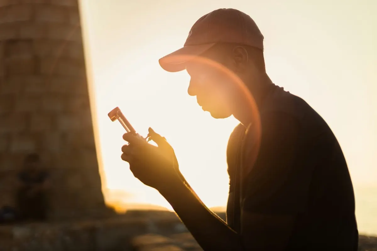 Athlete silhouetted at sunset checking a fitness tracker after training