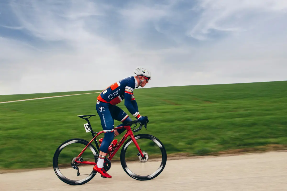 Cyclist pushing hard at threshold intensity on a road through green fields