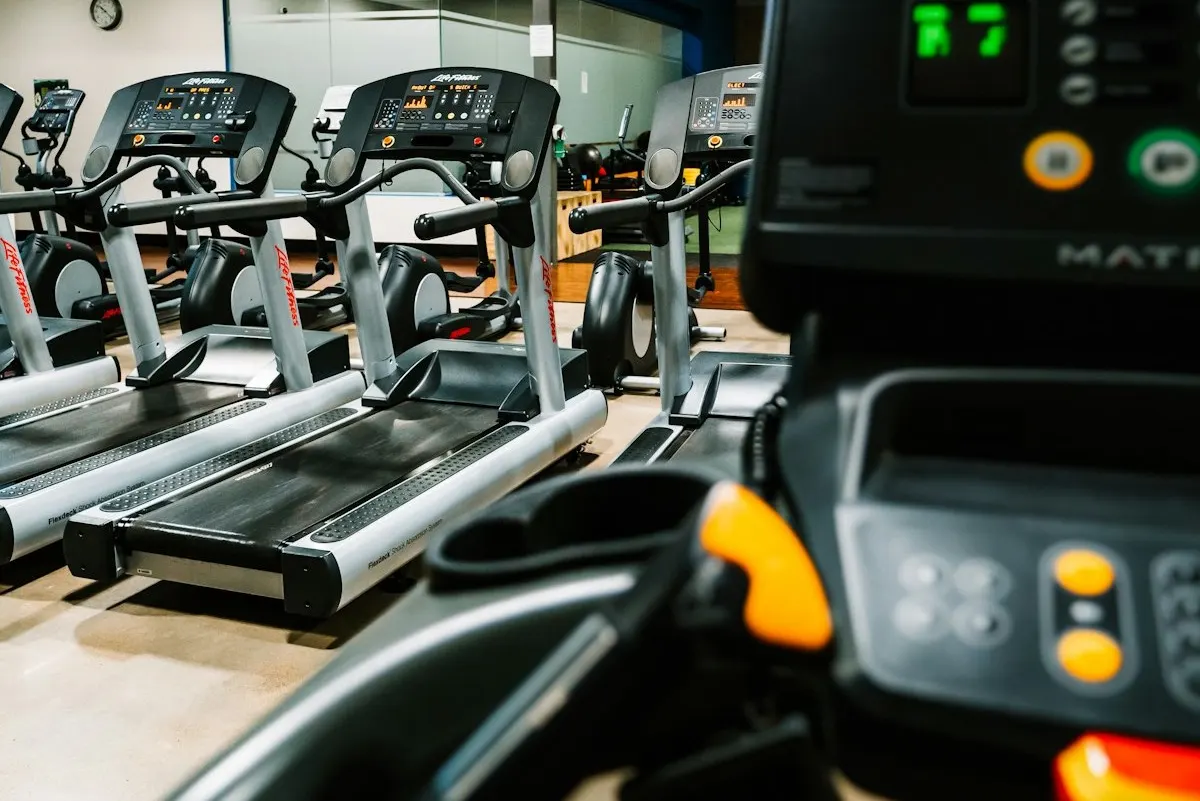 A person running on a treadmill in a gym, where indoor VO2 max tracking matters