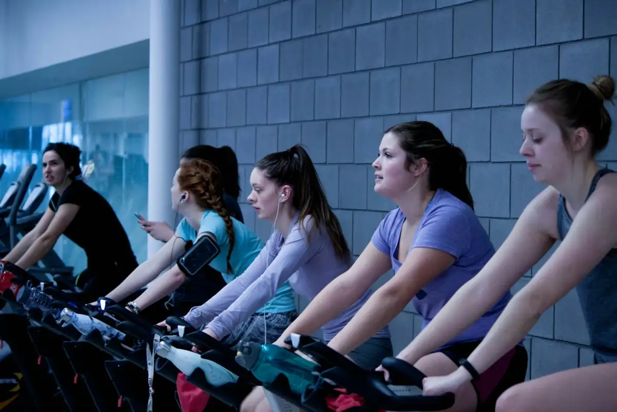 Women sprinting on stationary bikes during an indoor cycling session