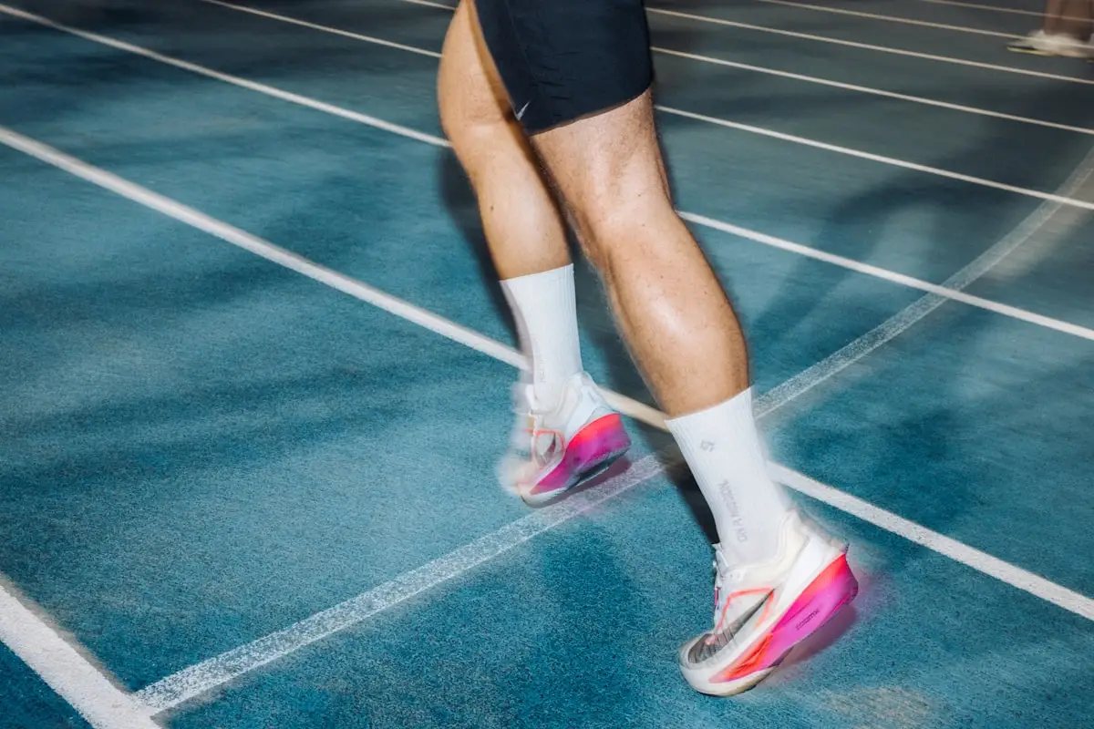 Athlete mid high-intensity interval, hands on knees and breathing hard between efforts